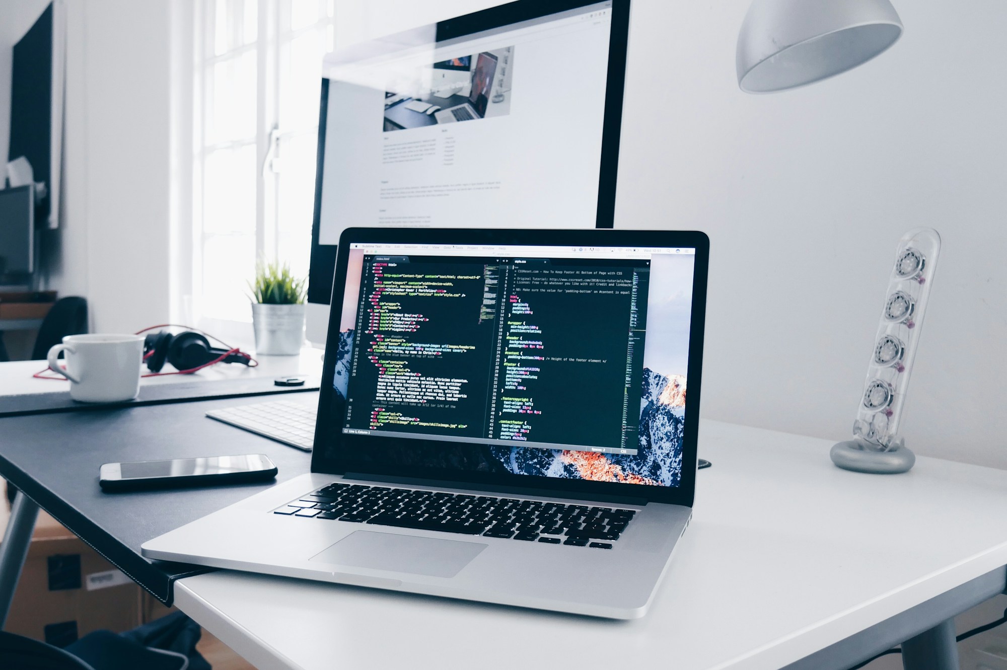 Laptop showing source code on a bright desk