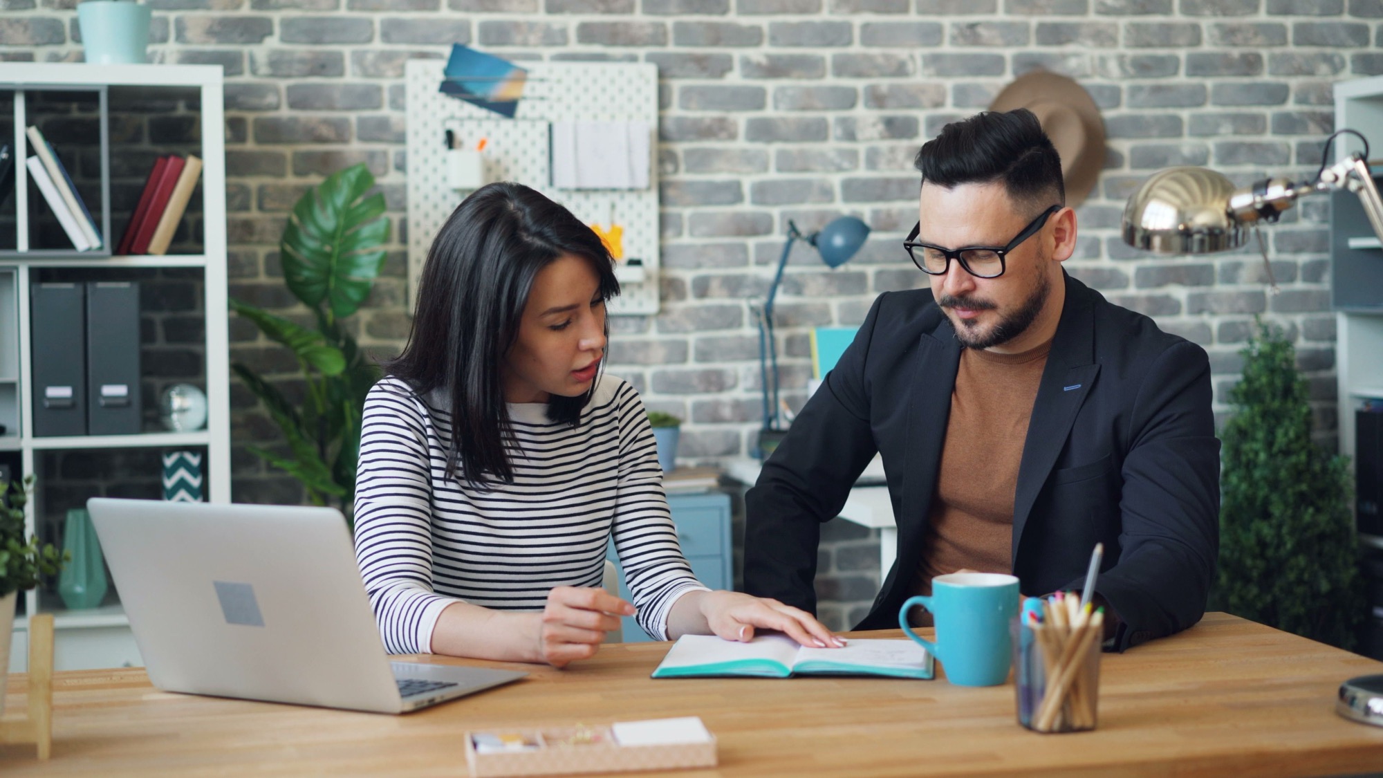 Two people talking through work at a laptop